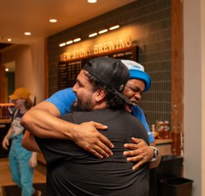 Two people sharing a warm, emotional hug, capturing a special moment at OKC Thunder Watch Party.