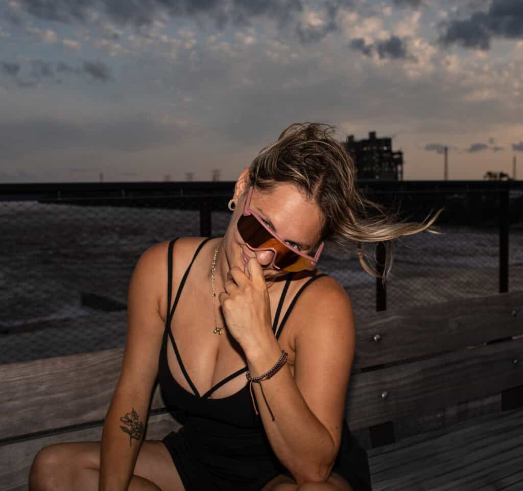 Woman in sunglasses laughing on a waterfront pier at dusk