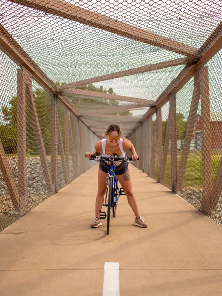 Woman riding a bicycle across a covered pedestrian bridge