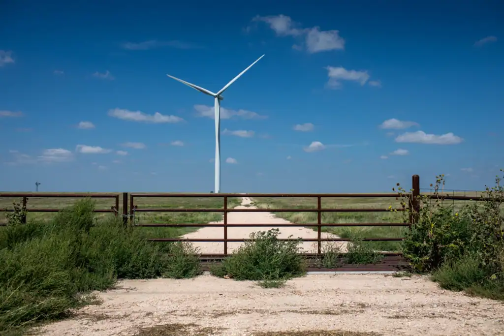 Wind turbine at the end of a gravel path under a blue sky