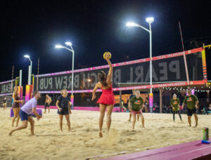 Action shot of a nighttime beach volleyball game under bright stadium lights, captured by an Oklahoma event photographer.