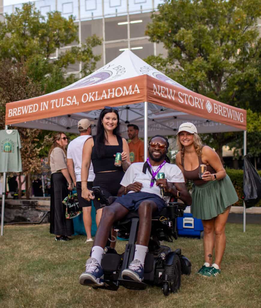 Friends gathered under a Brewed in Tulsa, Oklahoma brewery tent at an outdoor festival