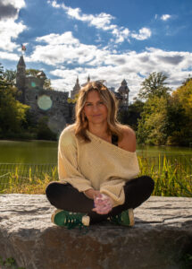 Outdoor portrait of a woman sitting on the grass and smiling, showcasing natural light photography.
