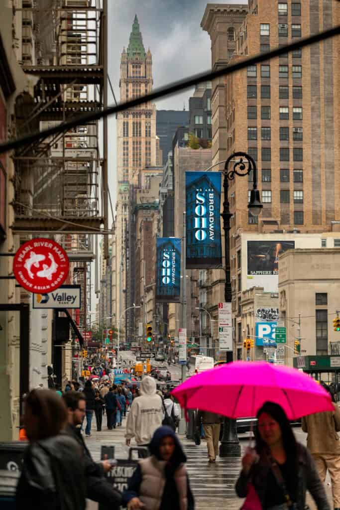 Pink umbrella on a busy downtown sidewalk lined with historic buildings