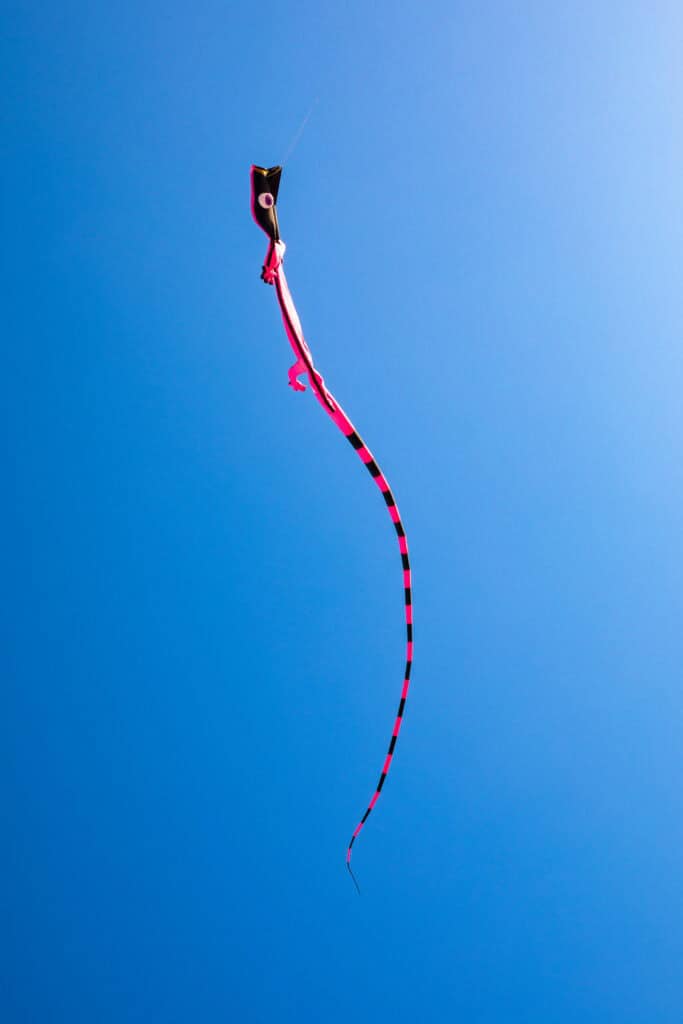 Colorful kite soaring high in a bright blue sky during a sunny day.