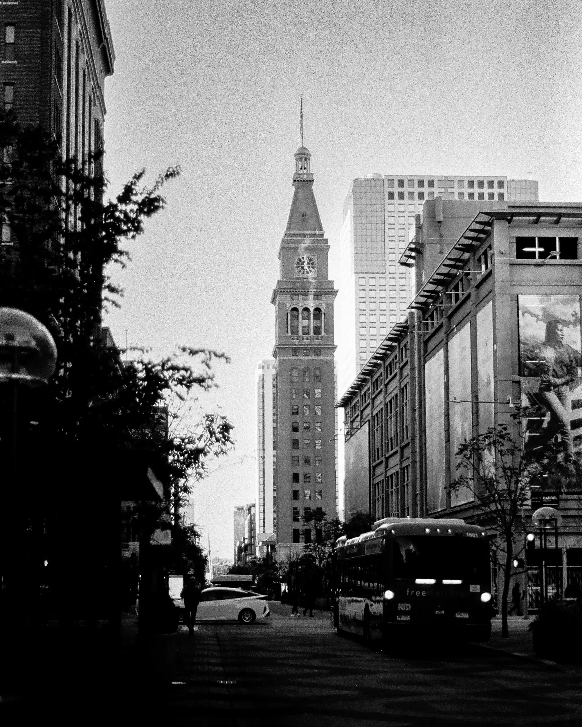 Black and white 35mm street photograph of a clock tower and city bus