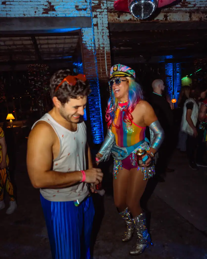 Joyful woman in colorful costume dancing with man at lively party event.
