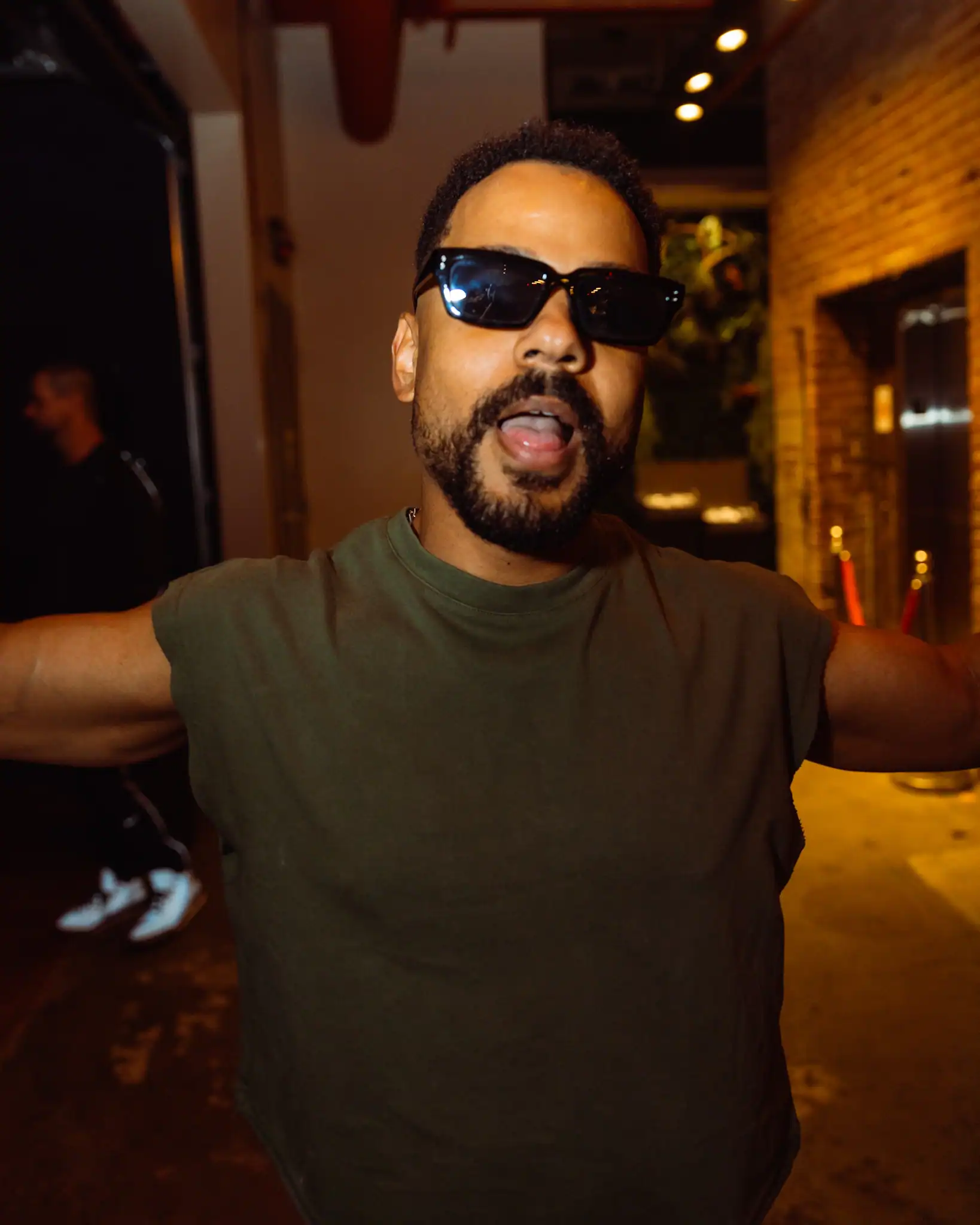 Portrait of a man wearing sunglasses and a green shirt in a studio setting.