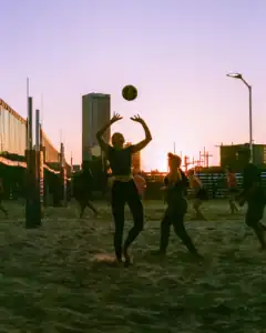 Beach volleyball players jumping for the ball during sunset in Oklahoma city.