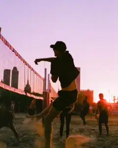 Beach volleyball player jumping during game at sunset.