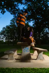 Young couple standing on park bench during sunset, enjoying each other's company.